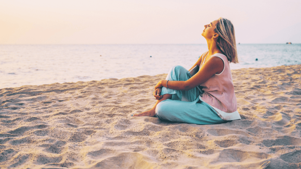 Mujer meditando en la playa, representando el poder del pensamiento positivo y la calma interior.